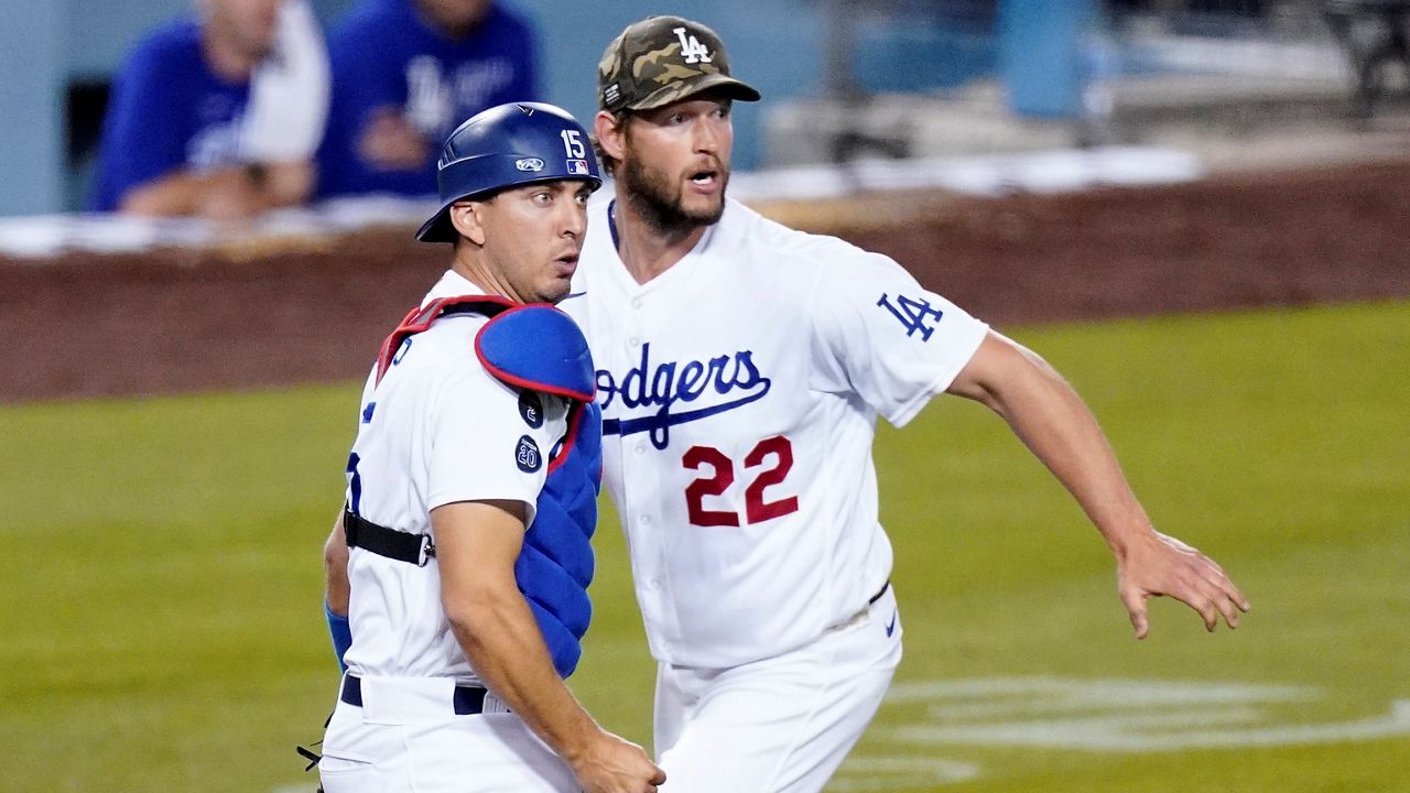 Los Angeles Dodgers catcher Austin Barnes, left, watches his throw to first along with starting pitcher Clayton Kershaw to get Miami Marlins' Adam Duvall out during the fifth inning of a baseball game, May 14, 2021, in LA. (AP Photo/Mark J. Terrill)