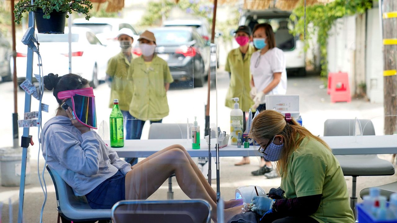 In this July 22, 2020, file photo, Tyson Salomon, left, gets a pedicure outside Pampered Hands nail salon in Los Angeles. California's top health official says the state will no longer require social distancing and will allow full capacity for businesses when the state reopens on June 15, 2021. (AP Photo/Ashley Landis, File)