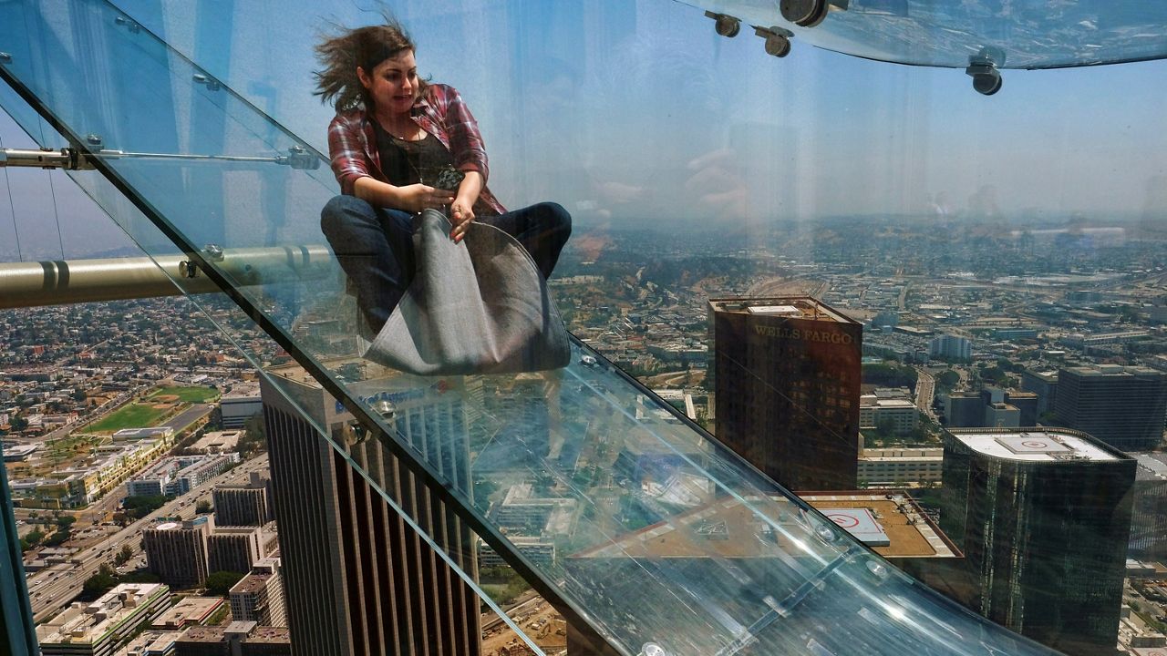 In this June 23, 2016, file photo, a member of the media rides down a glass slide during a media preview at the U.S. Bank Tower building in downtown Los Angeles. A renovation will do away with the Skyslide, located nearly 1,000 feet high outside of a downtown Los Angeles skyscraper. (AP Photo/Richard Vogel, File)