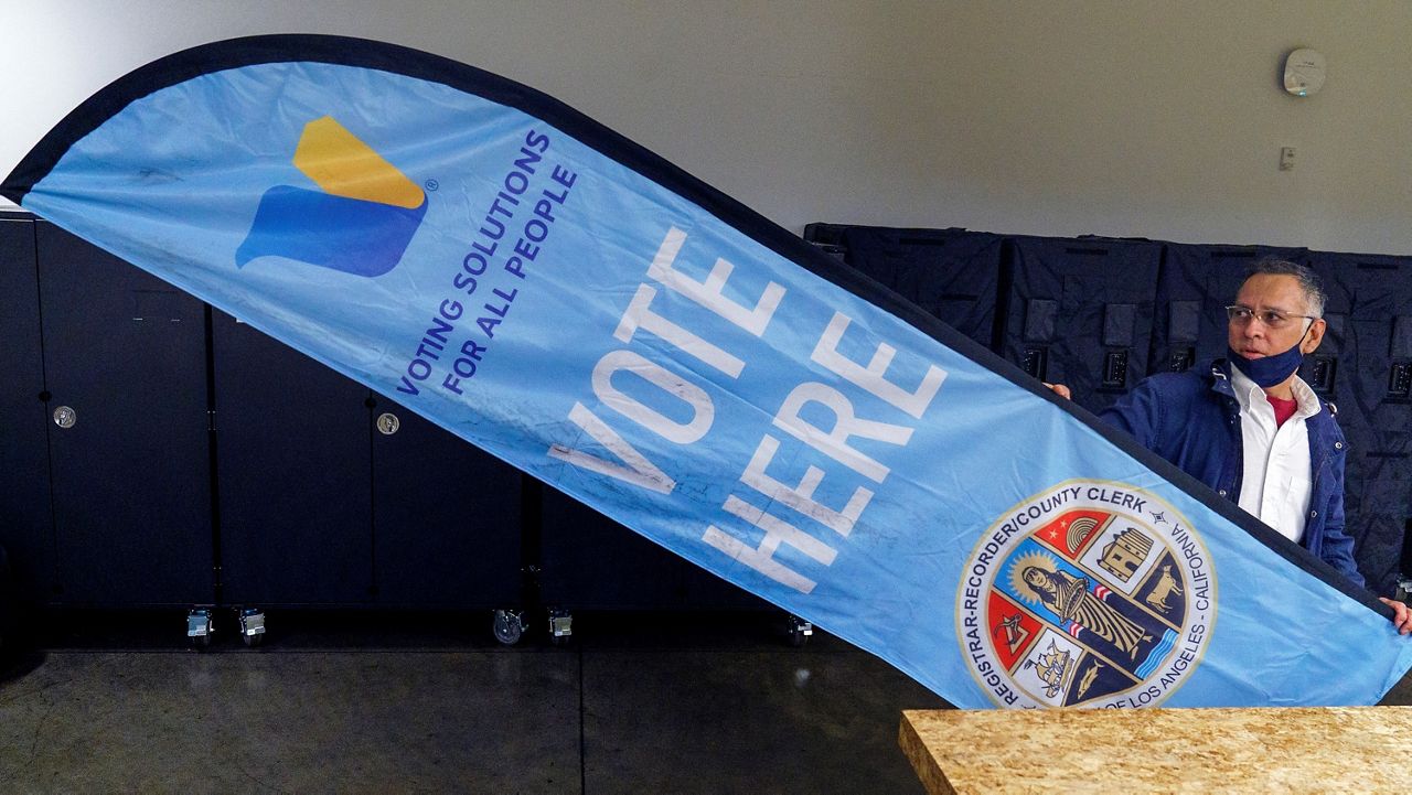 In this Nov. 3, 2020, file photo, Fernando Dejo takes down a "Vote Here" banner for storage as a polling place closes in Los Angeles. (AP Photo/Damian Dovarganes)