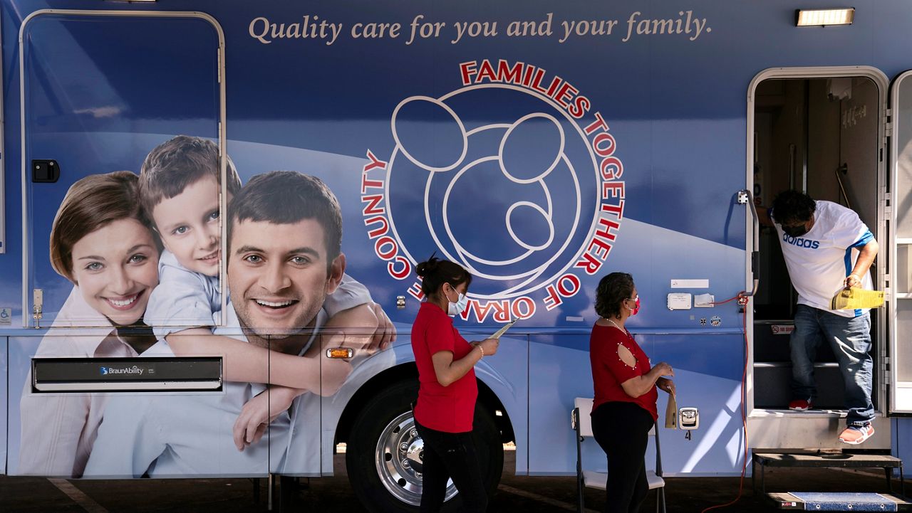 In this April 29, 2021, file photo, two women wait in line to receive a dose of the Moderna COVID-19 vaccine at a mobile clinic set up in the parking lot of a shopping center in Orange, Calif. (AP Photo/Jae C. Hong)