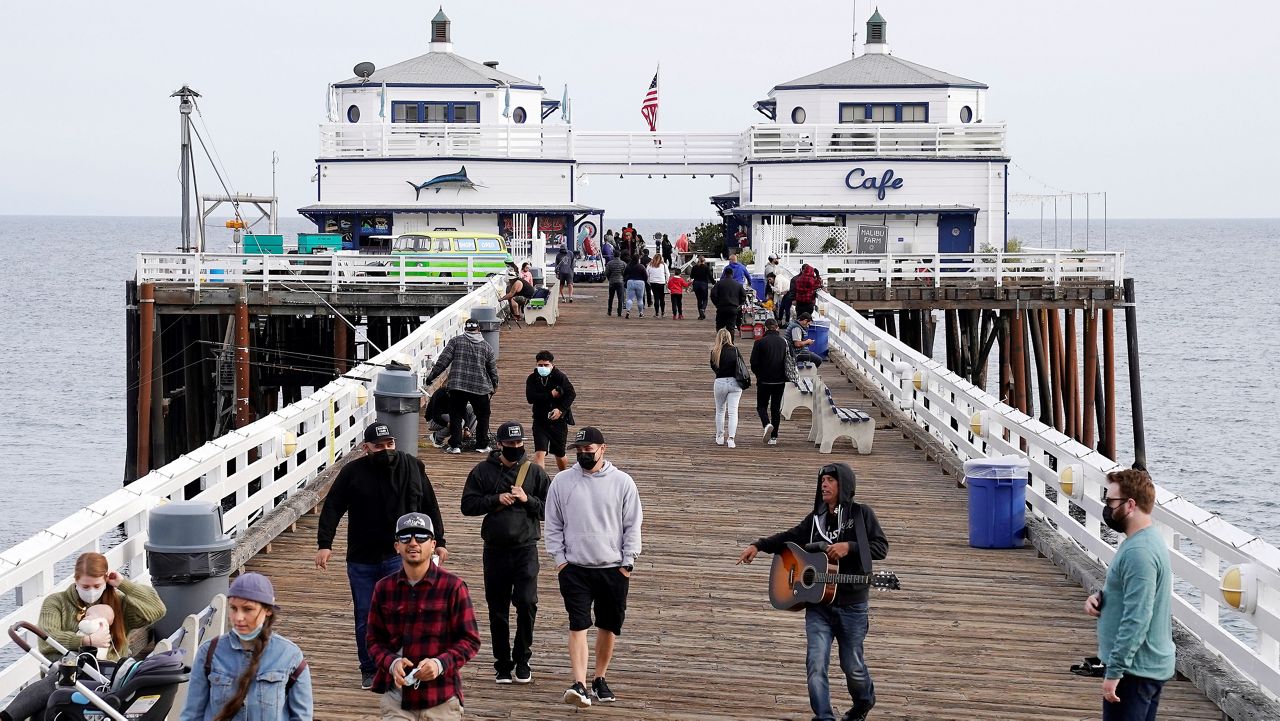 In this March 14, 2021, file photo, people walk on the Malibu Pier in the Malibu section of Los Angeles. (AP Photo/Mark J. Terrill)