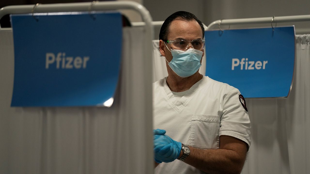 In this May 21, 2021 photo, student nurse Dario Gomez pauses while administering the Pfizer COVID-19 vaccine to patients at Providence Edwards Lifesciences vaccination site in Santa Ana. (AP Photo/Jae C. Hong)