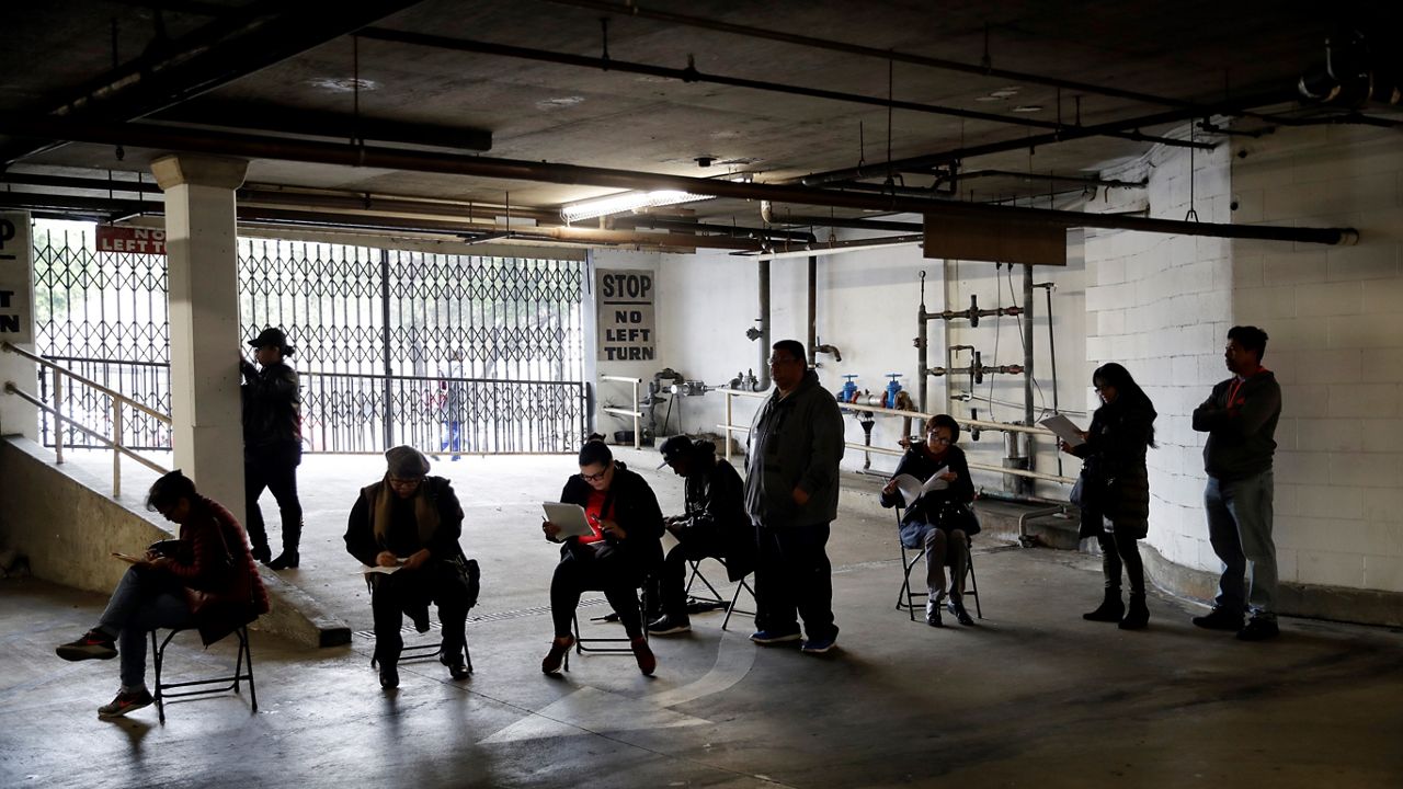 In this March 13, 2020, file photo, unionized hospitality workers wait in line in a basement garage to apply for unemployment benefits at the Hospitality Training Academy in Los Angeles. (AP Photo/Marcio Jose Sanchez, File)