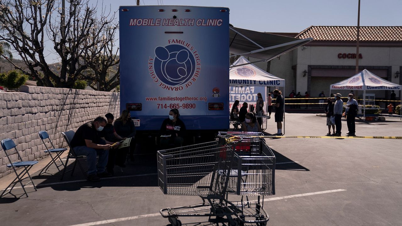 In this April 29, 2021, file photo, recipients hold in the observation area after receiving the Moderna COVID-19 vaccine at a mobile clinic set up in the parking lot of a shopping center in Orange, Calif. (AP Photo/Jae C. Hong)