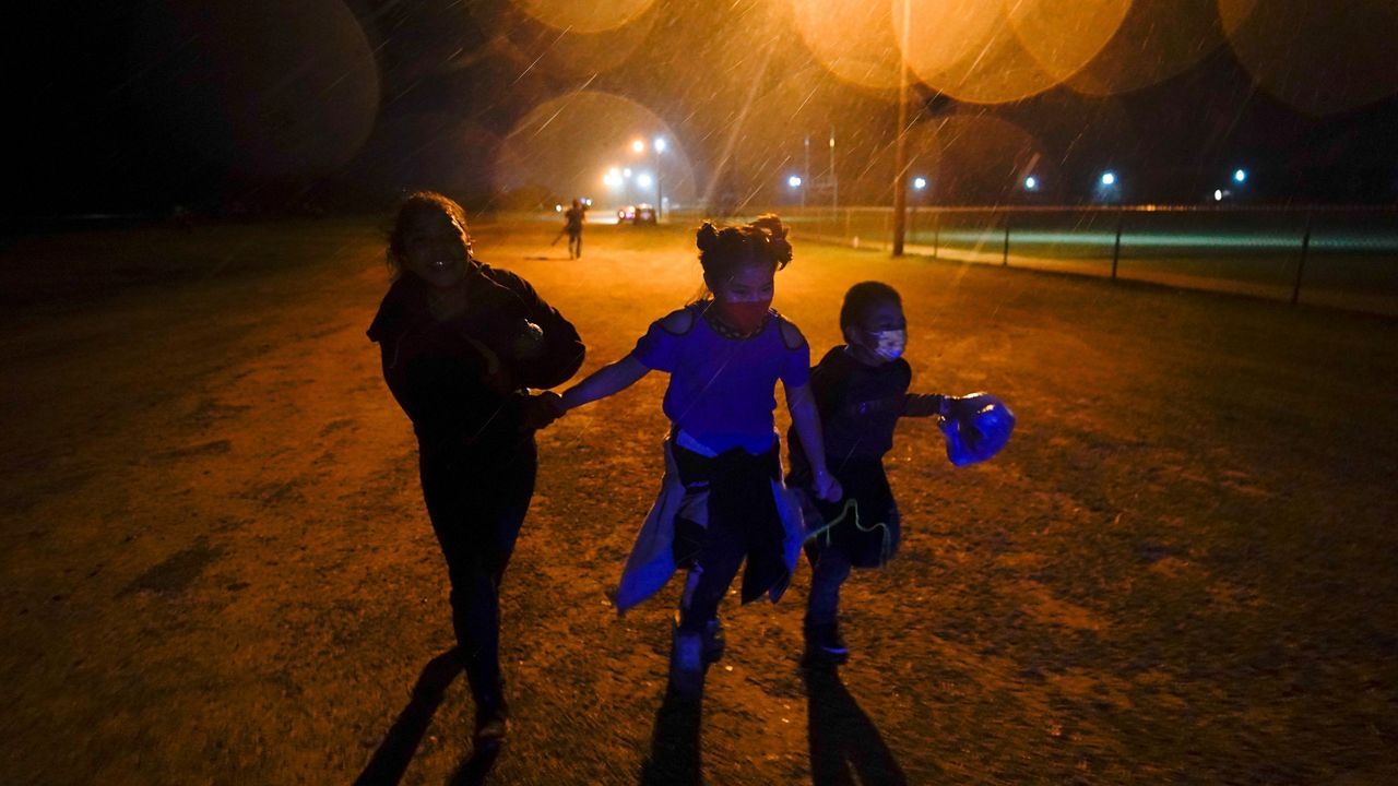 FILE - In this May 11, 2021, file photo, three young migrants hold hands as they run in the rain at an intake area after turning themselves in upon crossing the U.S.-Mexico border in Roma, Texas. (AP Photo/Gregory Bull, File)