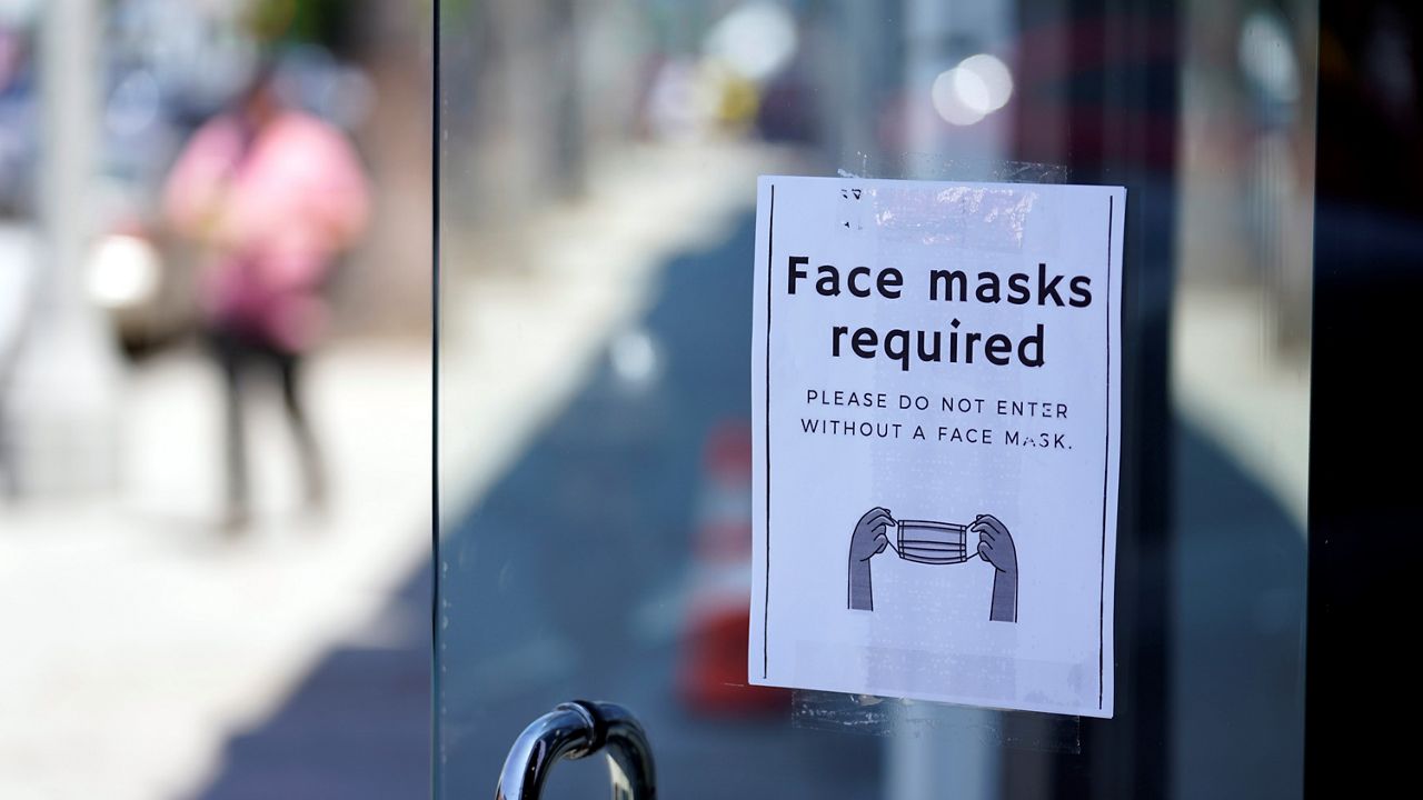 This July 19, 2021, photo shows a sign outside a store advising shoppers to wear masks in the Fairfax district of Los Angeles. (AP Photo/Marcio Jose Sanchez)