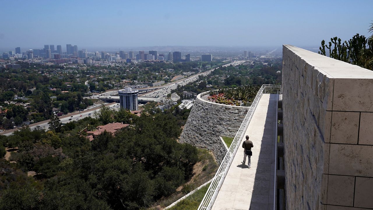 In this May 26, 2021, file photo, a visitor strolls along a walkway overlooking the city at the reopened Getty Center in Los Angeles amid the COVID-19 pandemic. (AP Photo/Marcio Jose Sanchez)