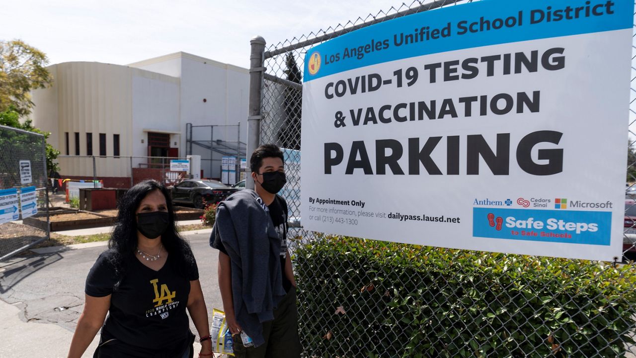 In this April 15, 2021, file photo, parent Rosa Vargas and her son, ninth grade student Victor Loredo, 14, walk home after getting tested at a Los Angeles Unified School District COVID-19 testing and vaccination site in East Los Angeles. (AP Photo/Damian Dovarganes)