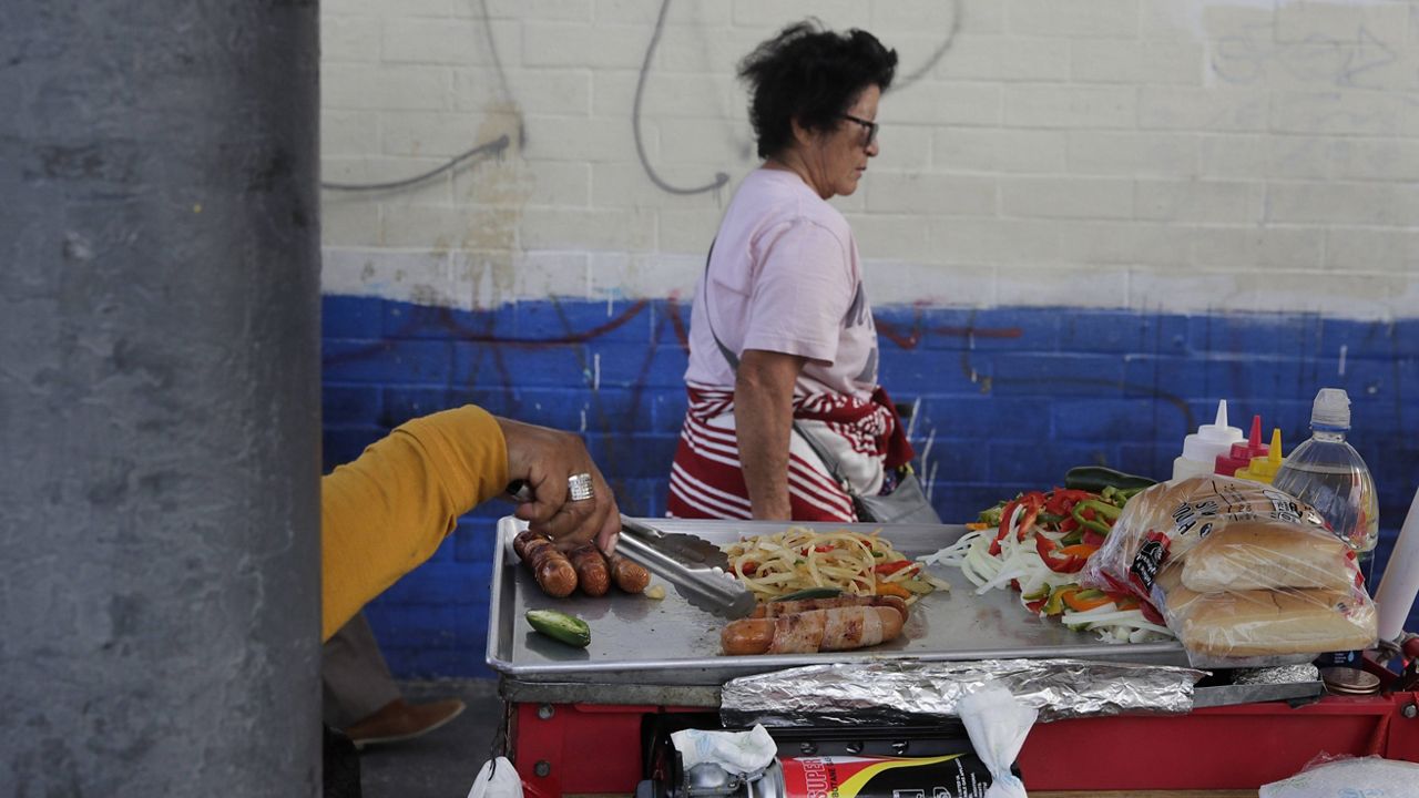 In this Nov. 27, 2018, file photo, a food vendor prepares hot dogs on a sidewalk in Los Angeles. (AP Photo/Jae C. Hong)