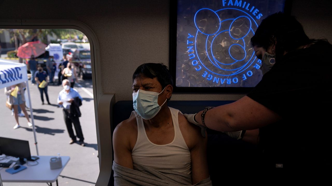 In this April 29, 2021, file photo, nurse Natasha Garcia administers a dose of the Moderna COVID-19 vaccine to Samuel Sanchez in a mobile clinic set up in the parking lot of a shopping center in Orange, Calif. (AP Photo/Jae C. Hong)