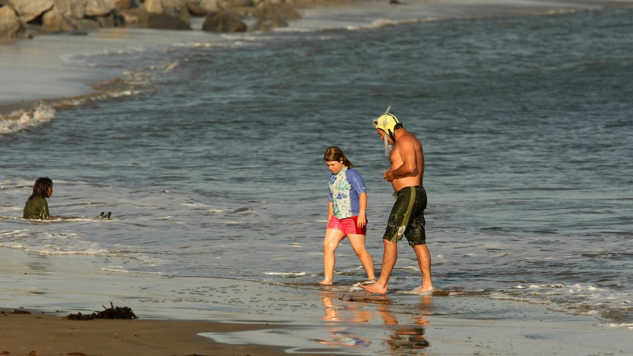 In this May 19, 2009, file photo, Cabrillo Beach Polar Bear club member Richard Havenick, right, with his child, Carly, leave the ocean on the open water side of Cabrillo Beach in Los Angeles. (AP Photo/Damian Dovarganes)