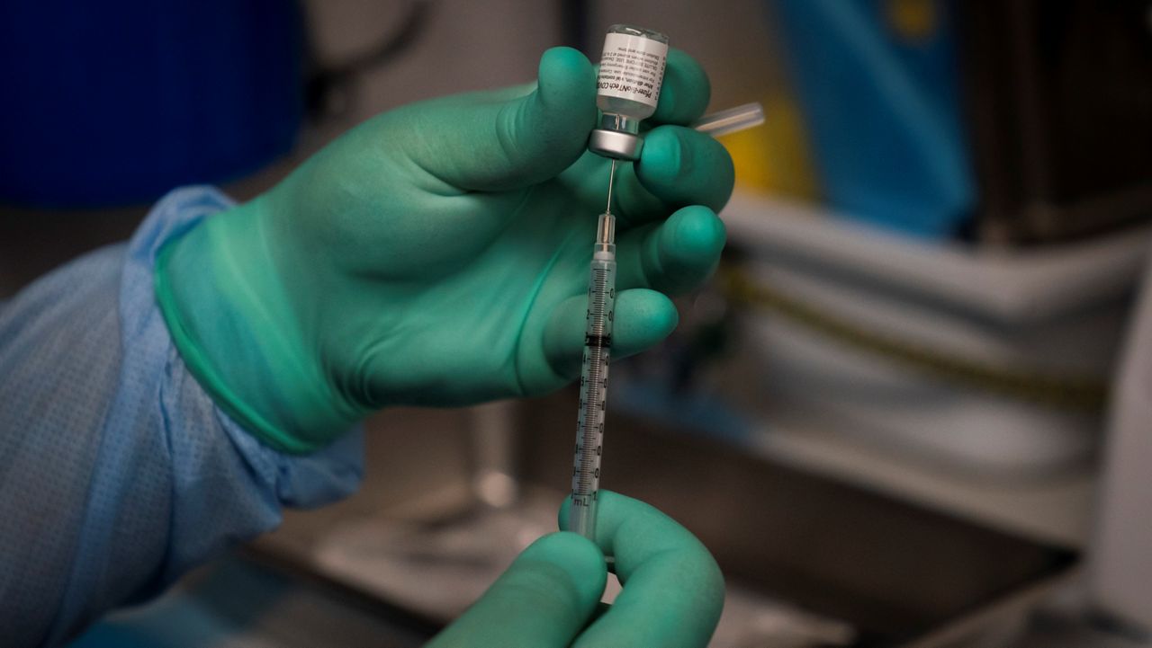 In this Aug. 26, 2021 photo, Parsia Jahanbani prepares a syringe with the Pfizer COVID-19 vaccine in a mobile vaccine clinic operated by Families Together of Orange County in Santa Ana, Calif. (AP Photo/Jae C. Hong)