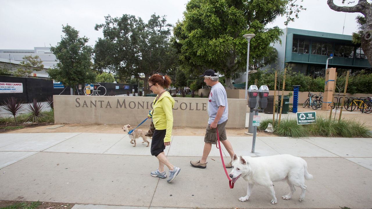 In this June 9, 2013, file photo, Karen Koblitz, 62, and her husband Al Friedenberg, 62, walk their dogs past Santa Monica College in Santa Monica, Calif. (AP Photo/Ringo H.W. Chiu)