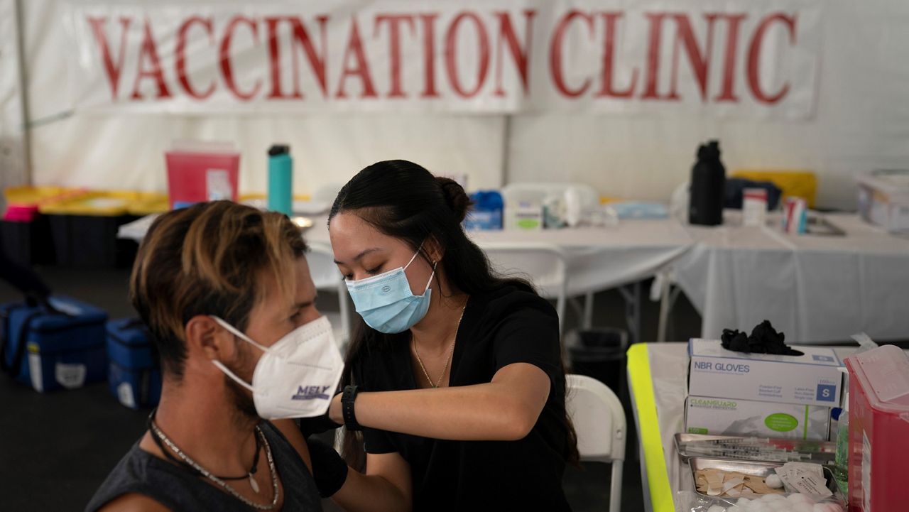 Registered nurse Noleen Nobleza, center, inoculates Julio Quinones with the COVID-19 vaccine at a clinic set up in the parking lot of CalOptima in Orange, Calif. on Aug. 28, 2021. (AP Photo/Jae C. Hong)