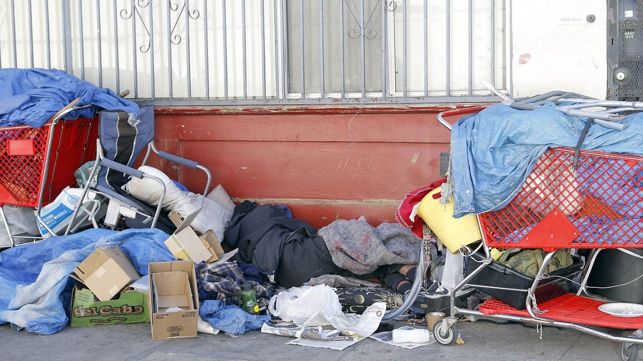 In this Feb. 28, 2013, file photo, a homeless man, center, sleeps among his possessions on Skid Row in Los Angeles. (AP Photo/Nick Ut)