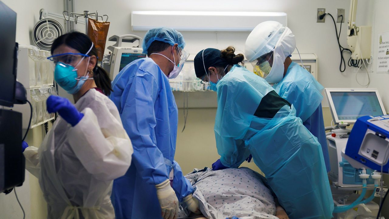 In this Nov. 19, 2020, file photo, emergency medical technician Giselle Dorgalli, second from right, performs chest compressions on a patient who tested positive for the coronavirus in the emergency room at Providence Holy Cross Medical Center in Los Angeles. (AP Photo/Jae C. Hong)