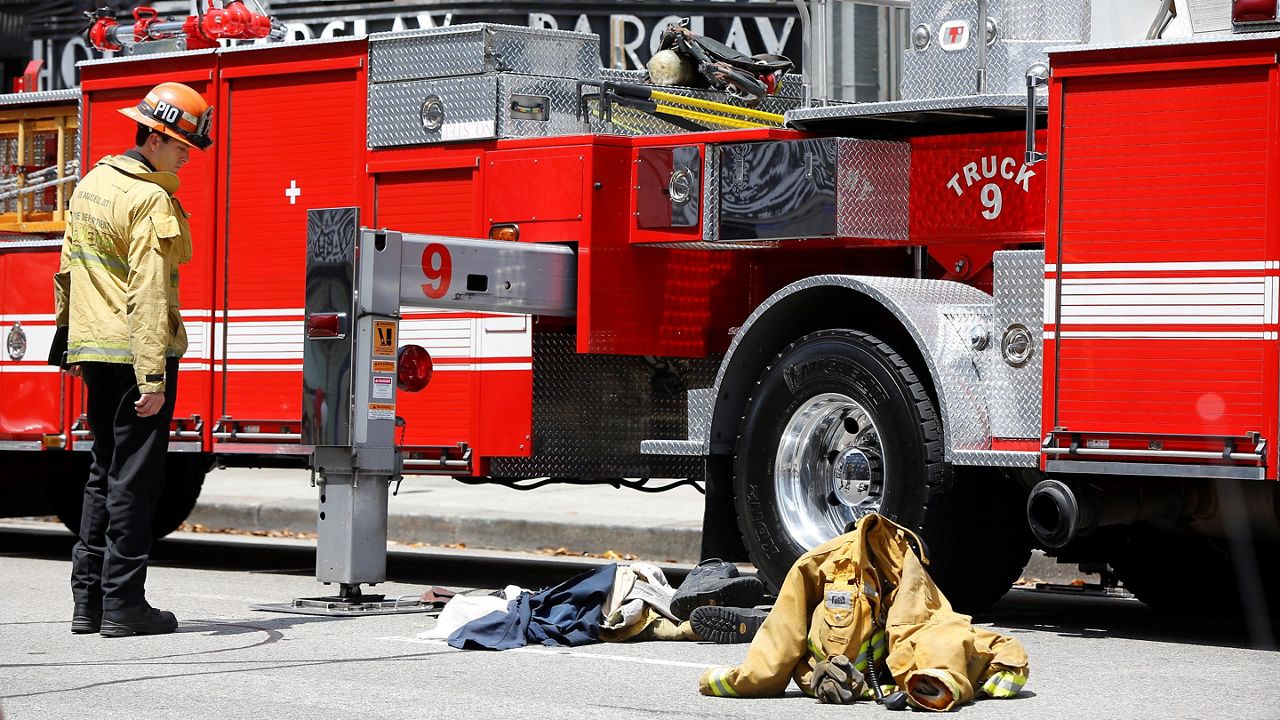 In this June 3, 2017, file photo, a Los Angeles Fire Department Public Information officer looks at the scene of a firefighter accident during a training exercise on Main Street in downtown Los Angeles. (AP Photo/Damian Dovarganes)