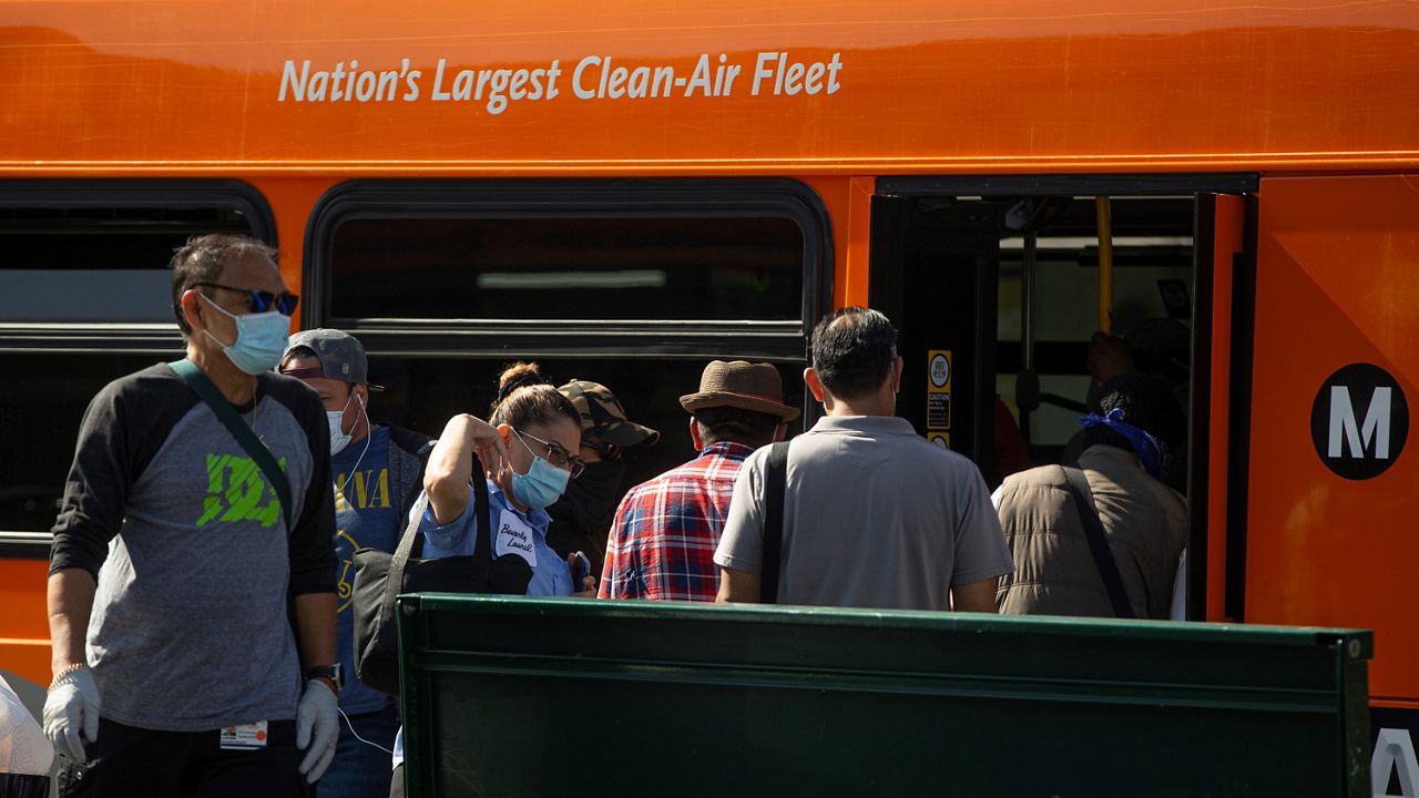 In this May 14, 2020, file photo, Los Angeles Metro commuters board a bus in Los Angeles. (AP Photo/Damian Dovarganes)