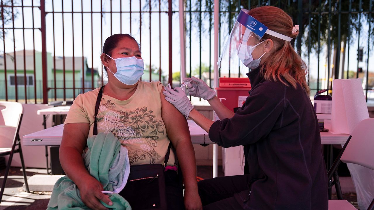 In this April 28, 2021, file photo, Juanita Ortega, left, receives the COVID-19 vaccine from registered nurse Anne-Marie Zamora at a Cedars-Sinai sponsored pop-up vaccine clinic at the Watts-Willowbrook Boys & Girls Club in Los Angeles. (AP Photo/Jae C. Hong)