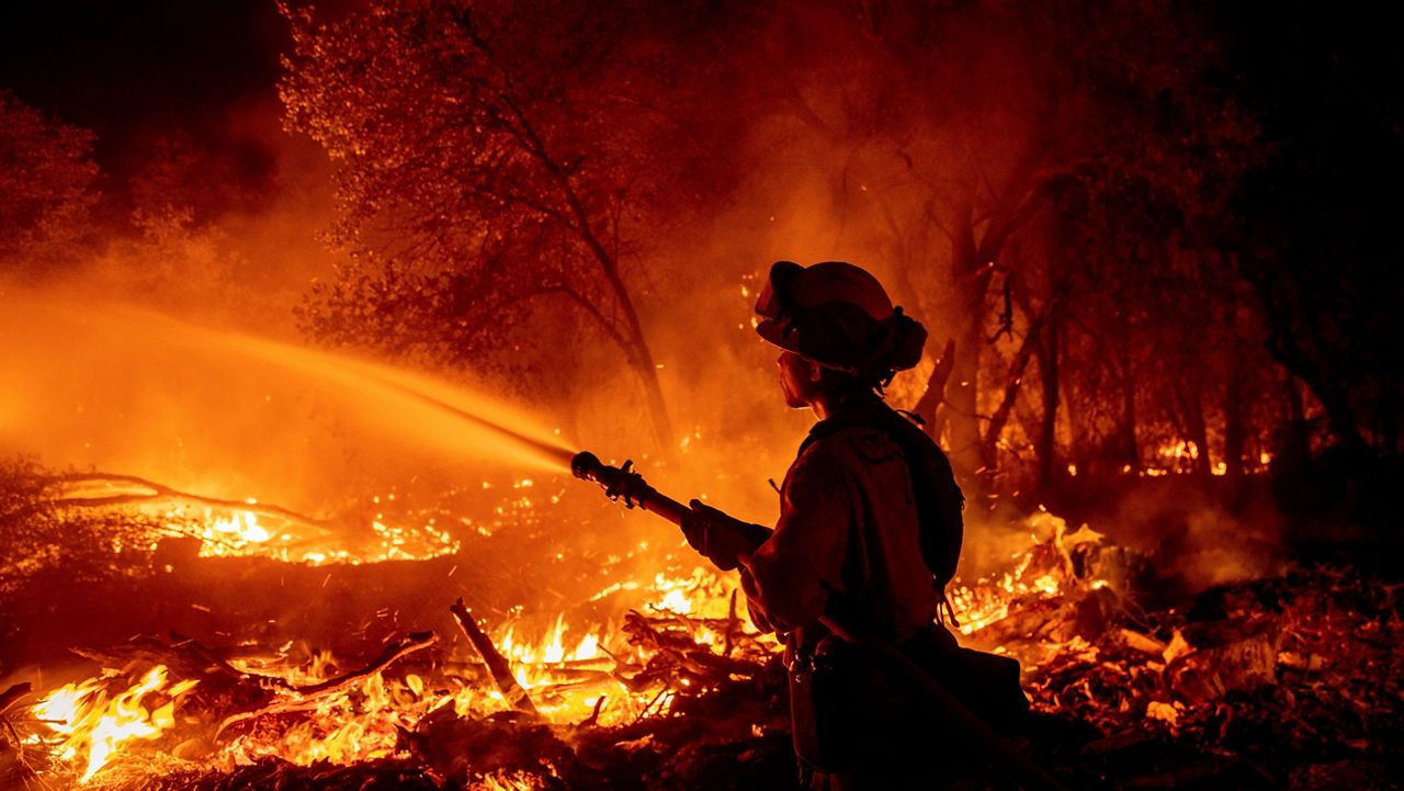 Firefighter Ron Burias battles the Fawn Fire Thursday as it spreads north of Redding, Calif. in Shasta County. (AP Photo/Ethan Swope)