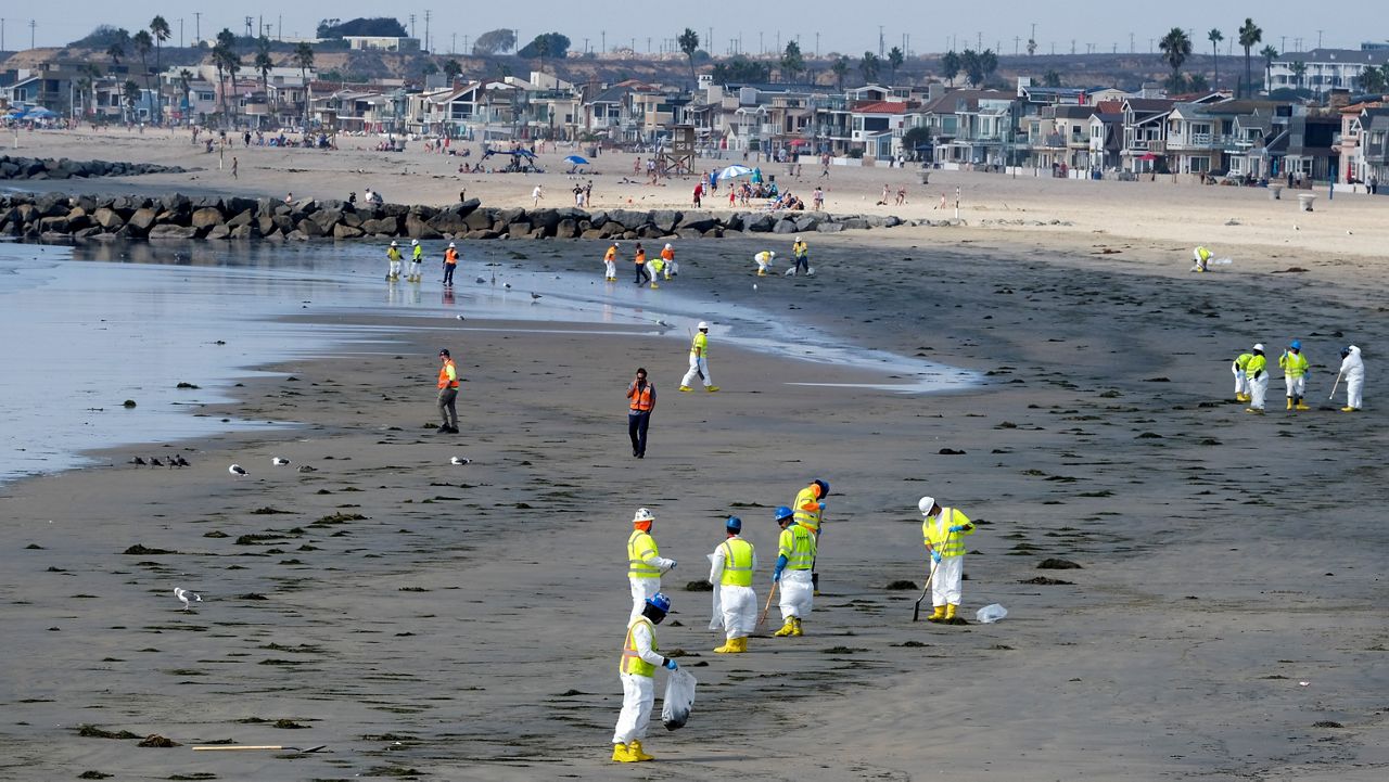 Workers in protective suits clean the contaminated beach after an oil spill, Wednesday, Oct. 6, 2021 in Newport Beach, Calif. A major oil spill off the coast of Southern California fouled popular beaches and killed wildlife while crews scrambled Sunday, to contain the crude before it spread further into protected wetlands. (AP Photo/Ringo H.W. Chiu)