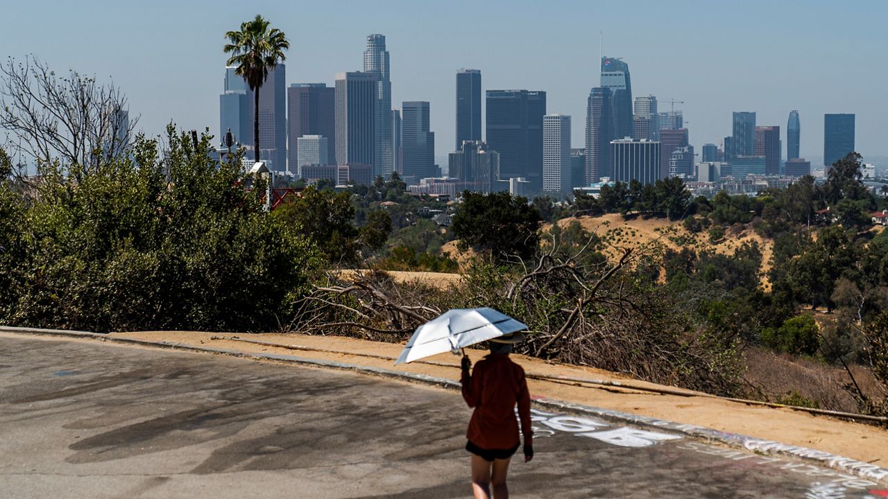 Athlete Sam Richardson uses a UV-Blocking Sun protection umbrella while speed-walking in Elysian Park in Los Angeles on July 7, 2021. (AP Photo/Damian Dovarganes)