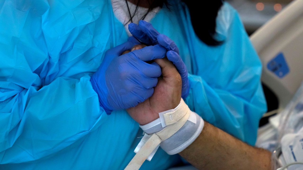 In this Feb. 15, 2021, file photo, Patty Trejo, 54, holds the hand of her intubated husband, Joseph, in a COVID-19 unit at St. Jude Medical Center in Fullerton, Calif. (AP Photo/Jae C. Hong)