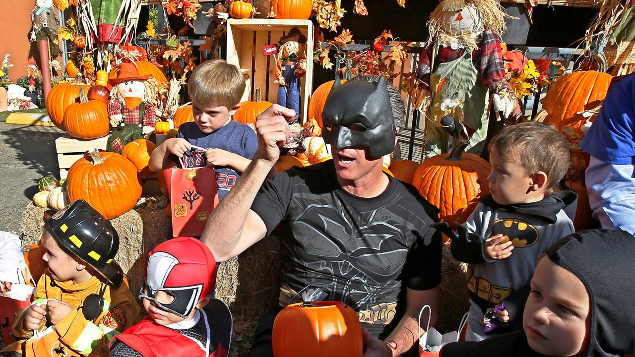 In this Oct. 31, 2018, file photo, then-Lt. Gov. Gavin Newsom, dressed as Batman, gets into the Halloween spirit as he hands out Halloween treats to costumed children during his visit to The Penleigh Child Development Center in Sacramento, Calif. (AP Photo/Rich Pedroncelli)