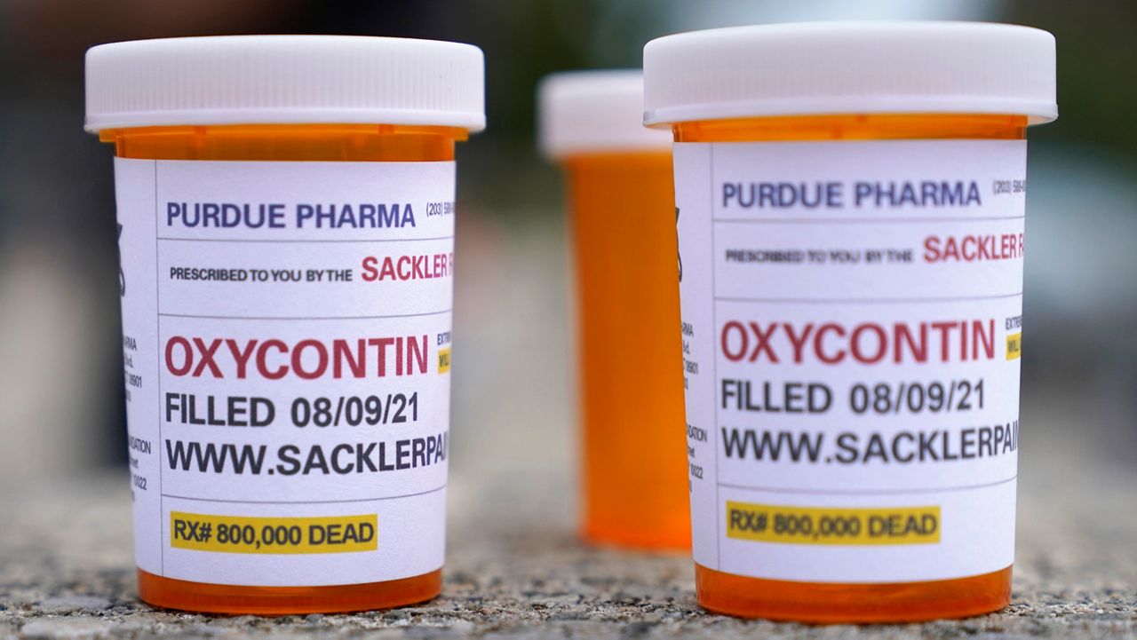 Fake pill bottles with messages about OxyContin maker Purdue Pharma are displayed during a protest outside the courthouse where the bankruptcy of the company is taking place in White Plains, N.Y., Aug. 9, 2021. (AP Photo/Seth Wenig)