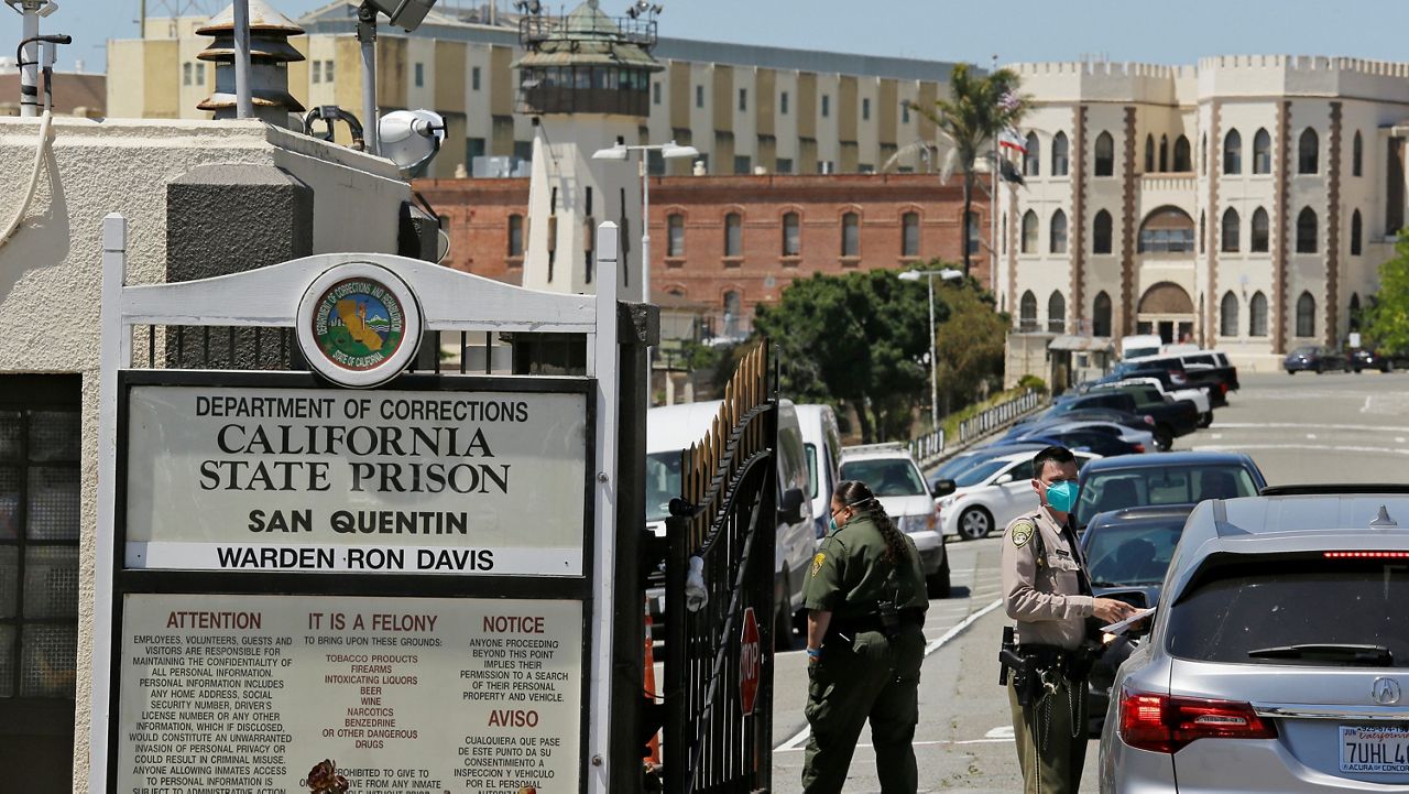 In this July 9, 2020, file photo, a correctional officer checks a car entering the main gate of San Quentin State Prison in San Quentin, Calif. (AP Photo/Eric Risberg)