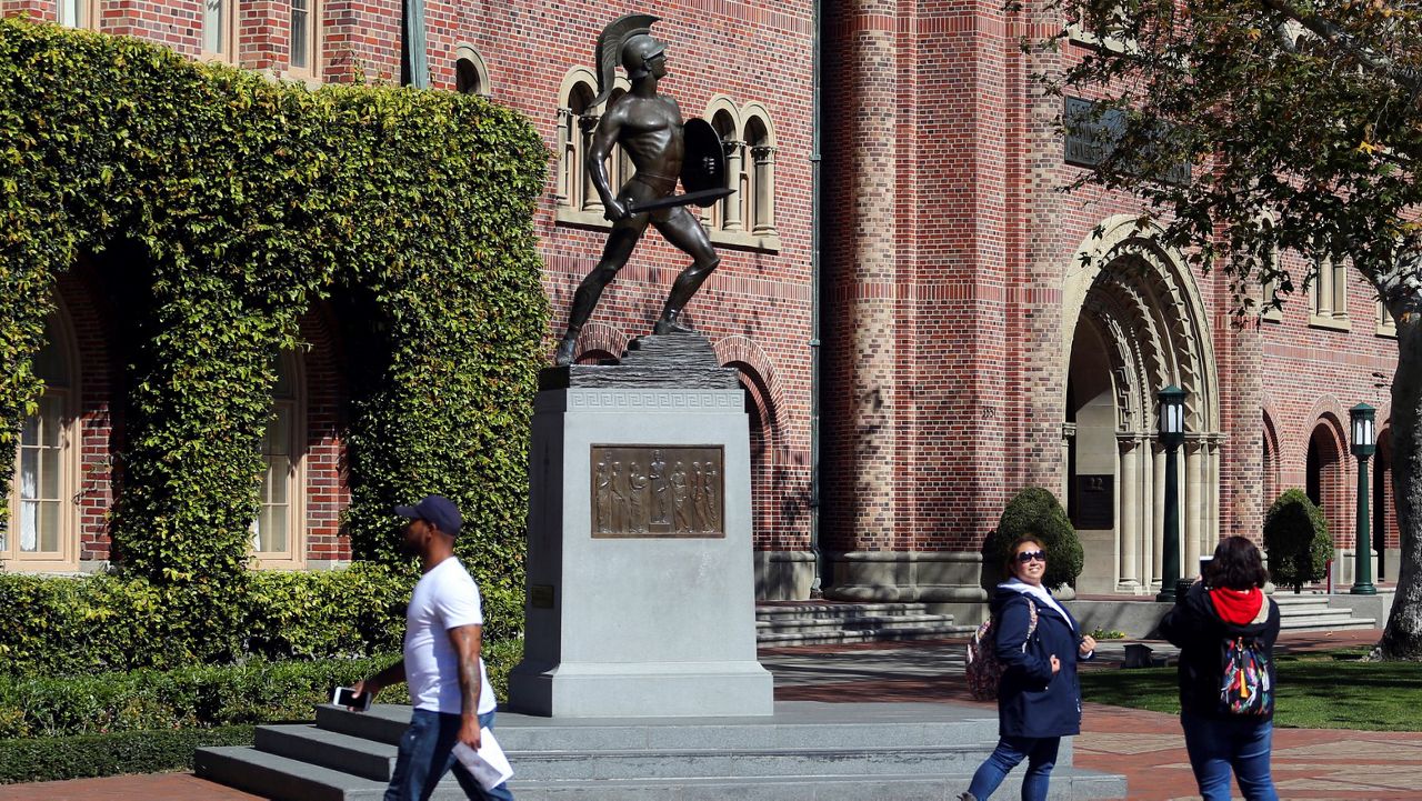 In this March 12, 2019, file photo, people pose for photos in front of the iconic Tommy Trojan statue on the University of Southern California campus in Los Angeles.  (AP Photo/Reed Saxon)