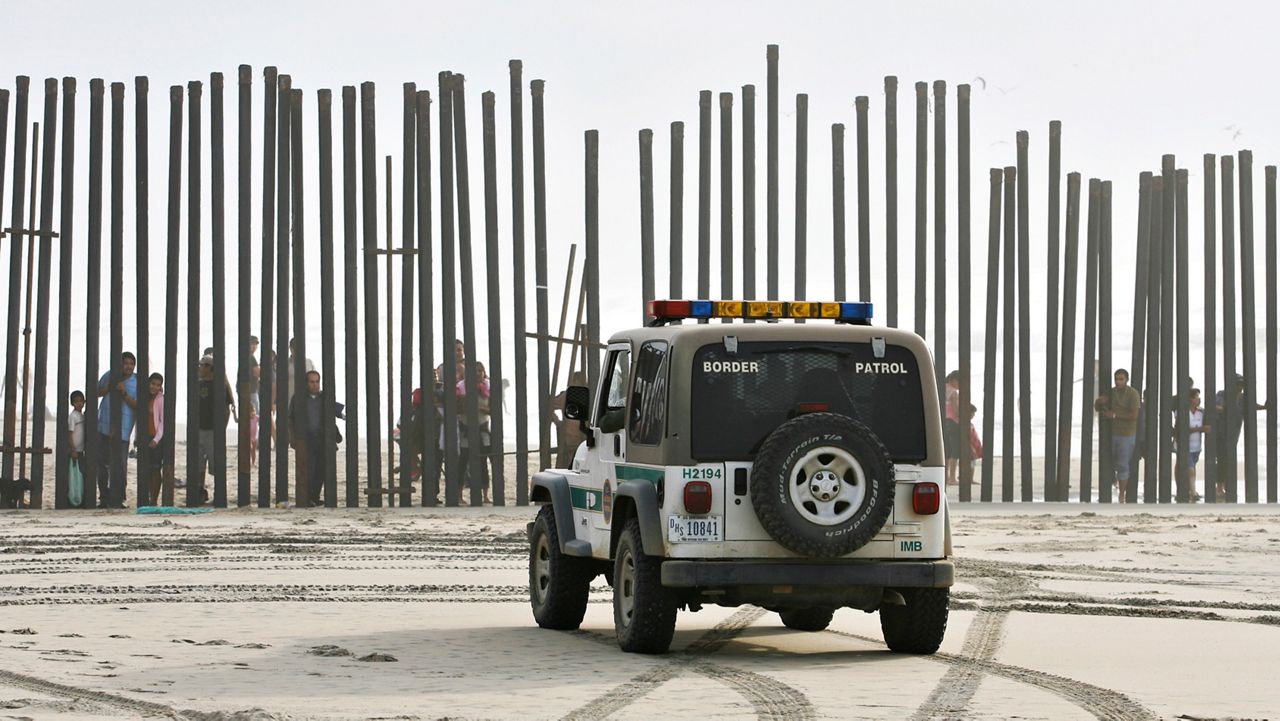 In this Jan. 18, 2009, file photo, a U.S. Border Patrol vehicle sits parked in front of a crowd of people peering through the U.S.-Mexico border fence at Border Field State Park in San Diego. (AP Photo/Denis Poroy)