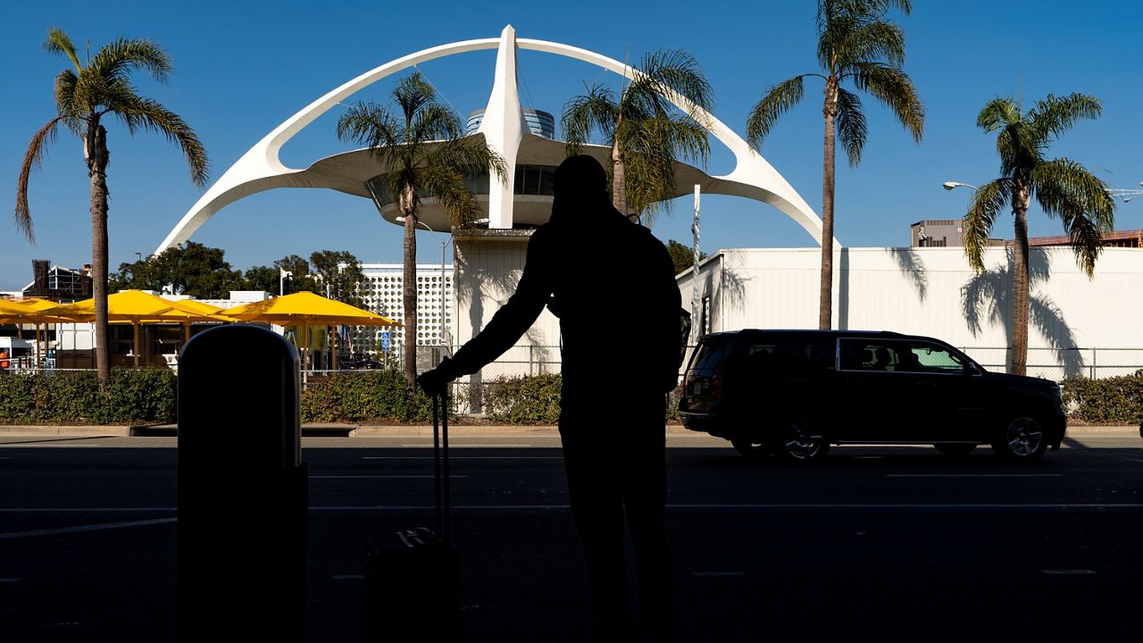 In this Nov. 25, 2020, file photo, a traveler awaits transportation at the Los Angeles International Airport in Los Angeles. (AP Photo/Damian Dovarganes)