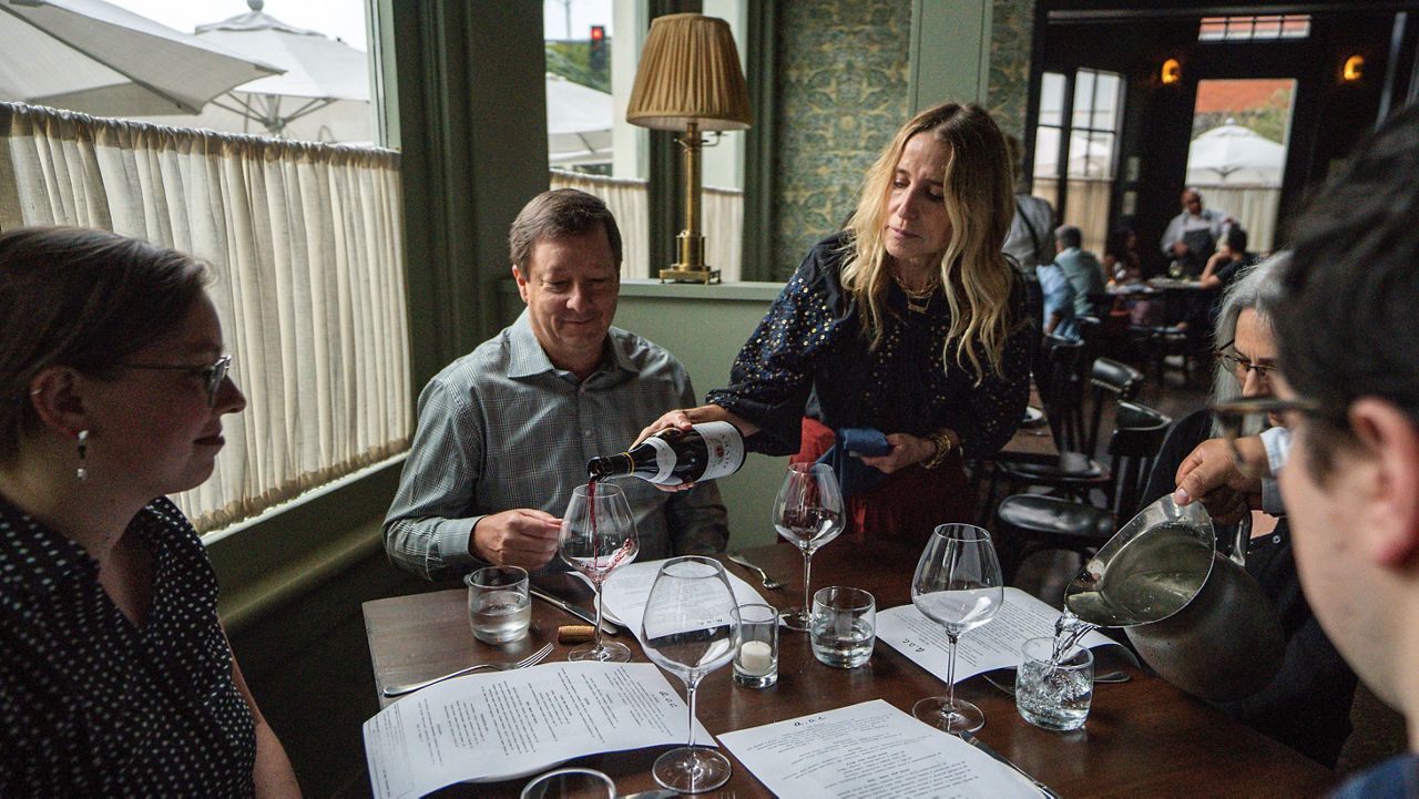 In this June 19, 2021, file photo, Caroline Styne, owner and wine director at The Lucques Group, serves wine to attorney Alec Nedelman at the A.O.C. (AP Photo/Damian Dovarganes)