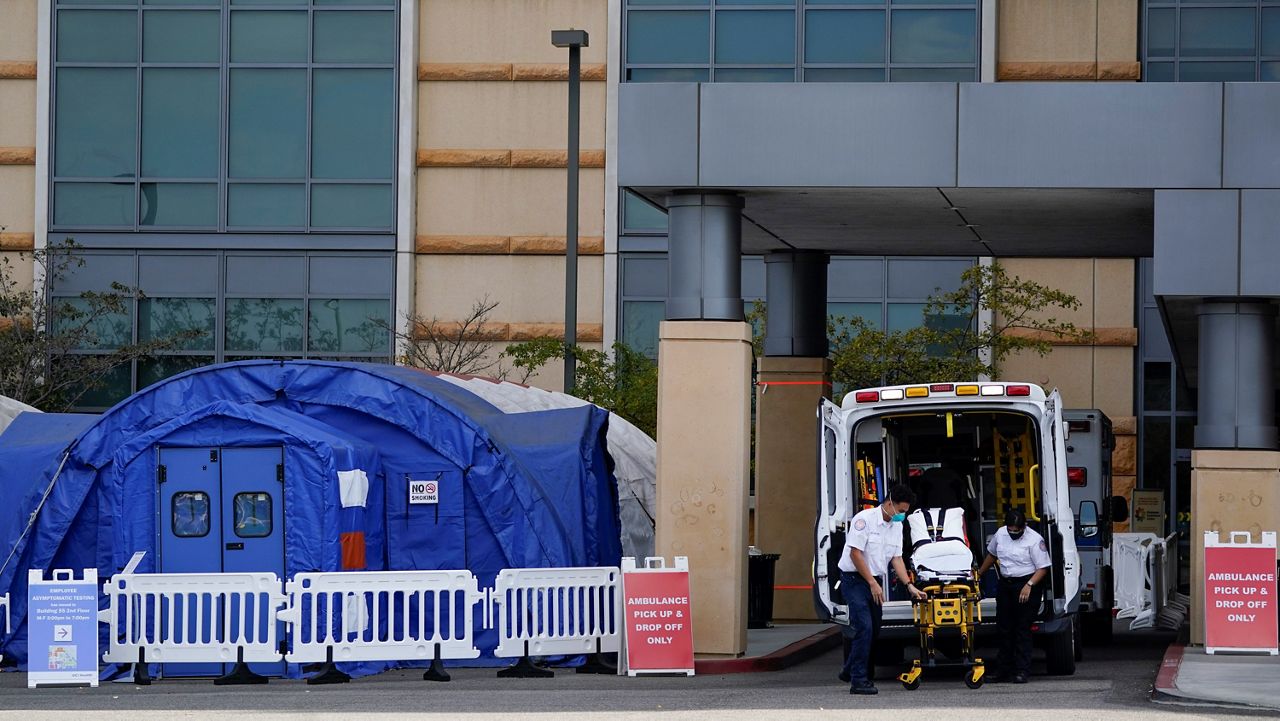 In this Dec. 17, 2020, file photo, medical workers remove a stretcher from an ambulance near medical tents outside the emergency room at UCI Medical Center in Irvine, Calif. (AP Photo/Ashley Landis)