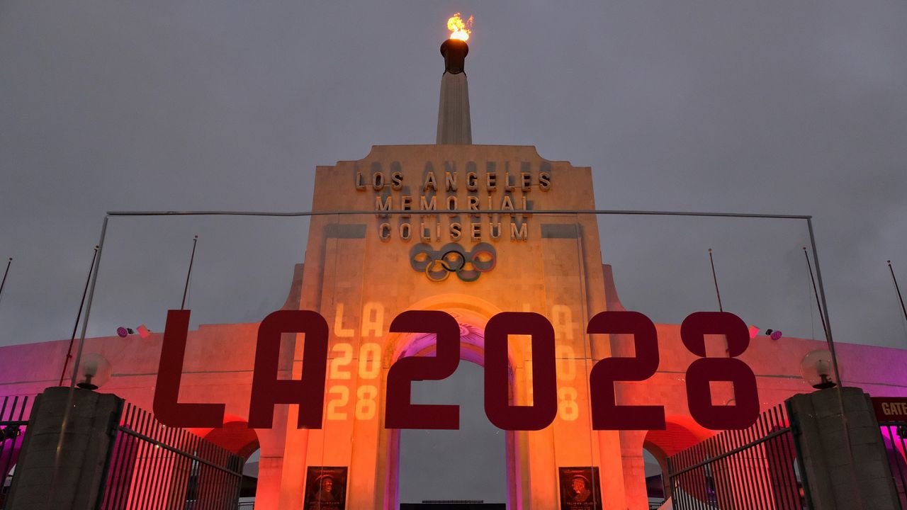 In this Sept. 13, 2017, file photo, an LA 2028 sign is seen in front of a blazing Olympic cauldron at the Los Angeles Memorial Coliseum. (AP Photo/Richard Vogel)