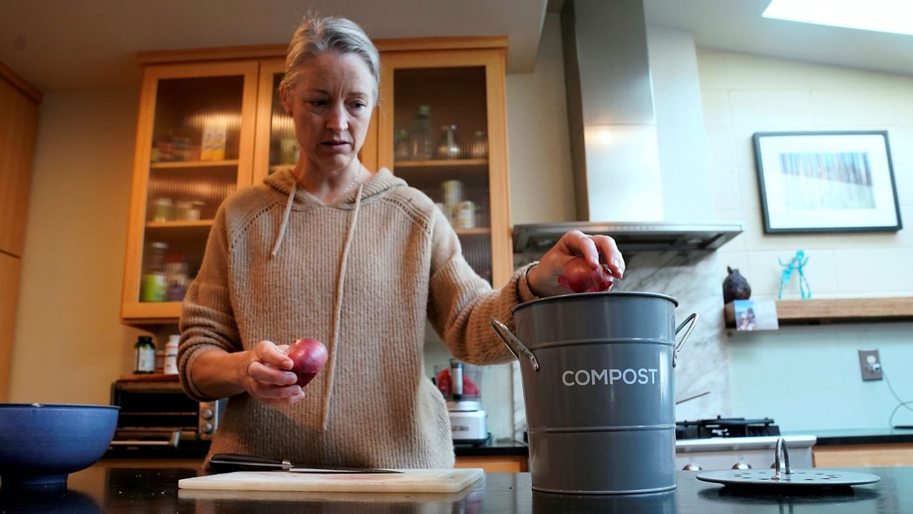 In this Nov. 30, 2021, file photo, Joy Klineberg tosses an onion peel into a container to be used for composting while preparing a family meal at her home in Davis, Calif. In January 2022, new rules take effect in California requiring people to recycle their food waste to be combusted or turned into energy. (AP Photo/Rich Pedroncelli)
