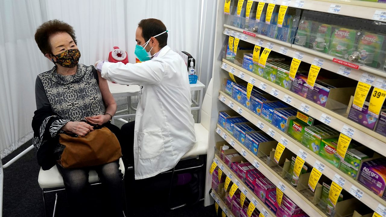 In this March 1, 2021, file photo, pharmacist Todd Gharibian, right, administers a dose of the Moderna COVID-19 vaccine to Toshiko Sugiyama, left, at a CVS Pharmacy branch in Los Angeles. (AP Photo/Marcio Jose Sanchez)