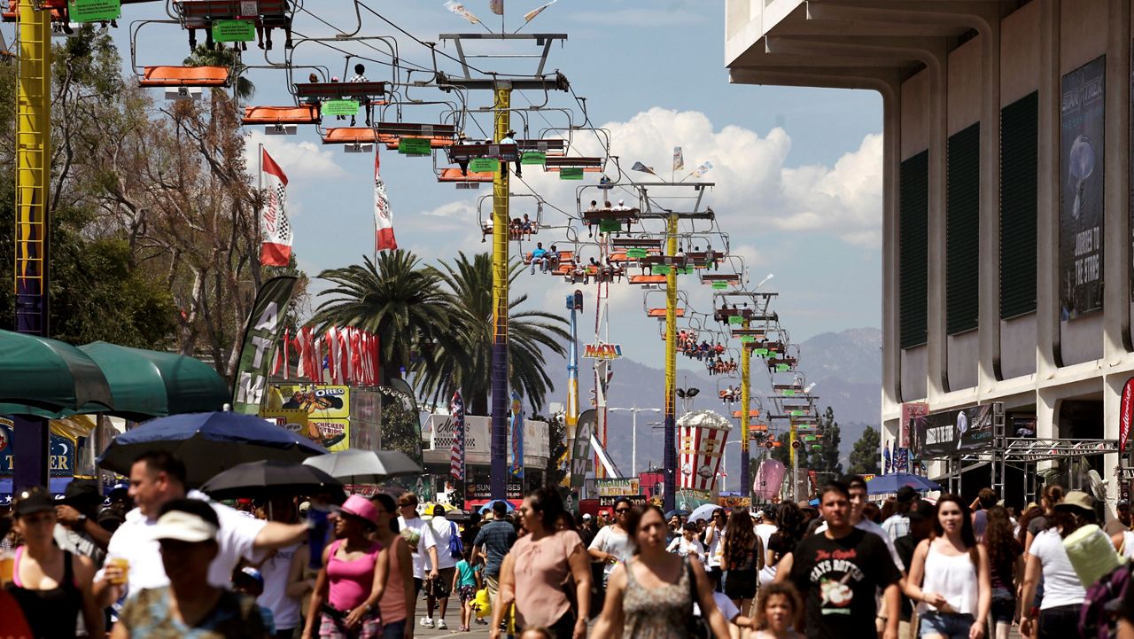 In this Sept. 2, 2013, file photo, fairgoers ride a tram over the crowds at the LA County Fair in Pomona, Calif. (AP Photo/Richard Vogel)