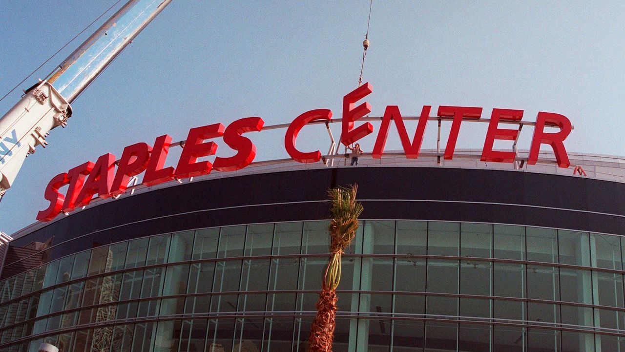 In this Nov. 16, 2021, file photo, construction workers put the finishing touches on the Staples Center sign outside the arena in downtown Los Angeles. Staples Center is getting a new name. Starting Christmas Day, it will be Crypto.com Arena. (AP Photo/Xerro Ryan Covarrubias)