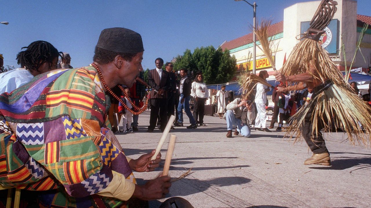 In this Dec. 26, 1997, file photo, traditional music is played as the Chi Wara, right, the antelope representing the new year, dances during the start of Kwanzaa in the Leimert Park area of Los Angeles. (AP Photo/Susan Goldman)