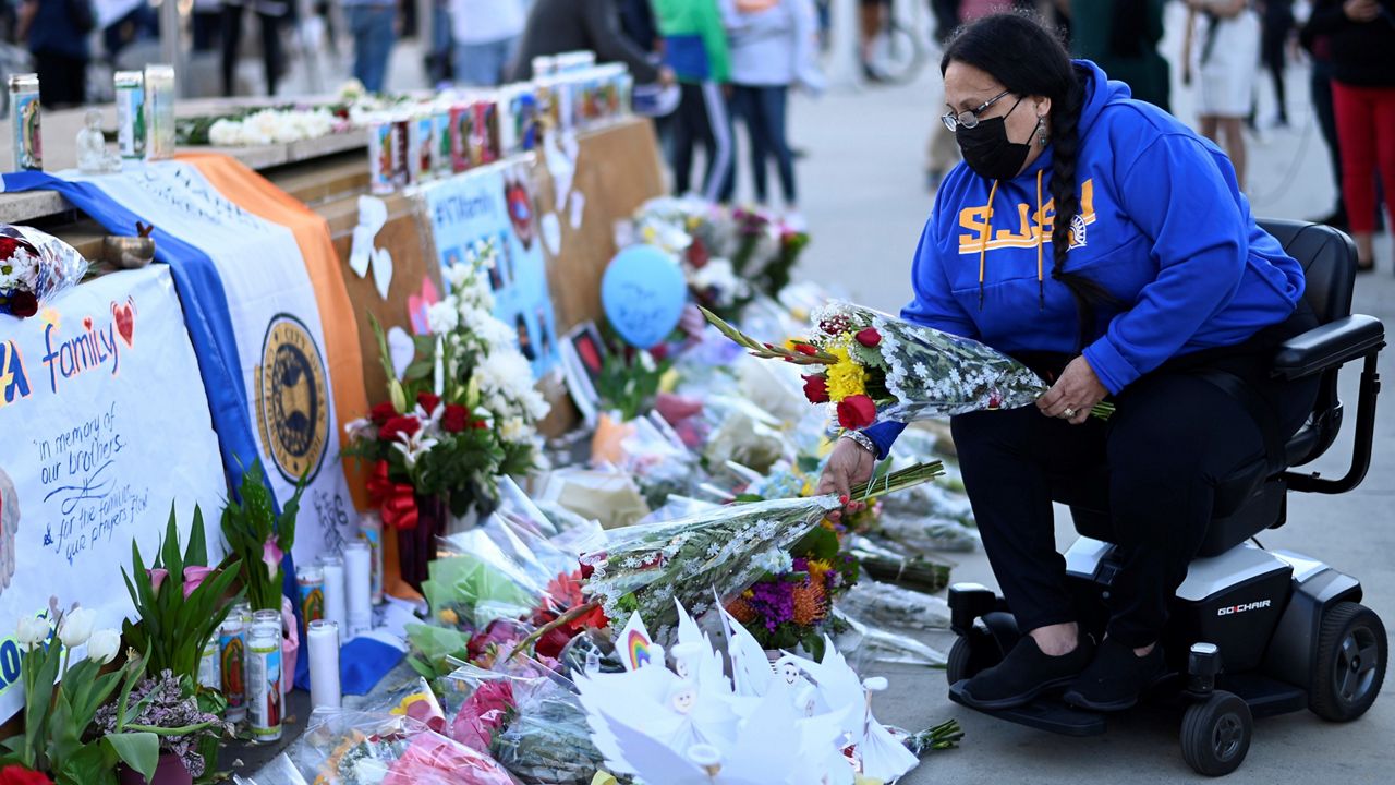 Diana Carreras places flowers Thursday at a vigil at City Hall in San Jose in honor of the multiple people killed when a gunman opened fire at a rail yard the day before. (AP Photo/Nic Coury)