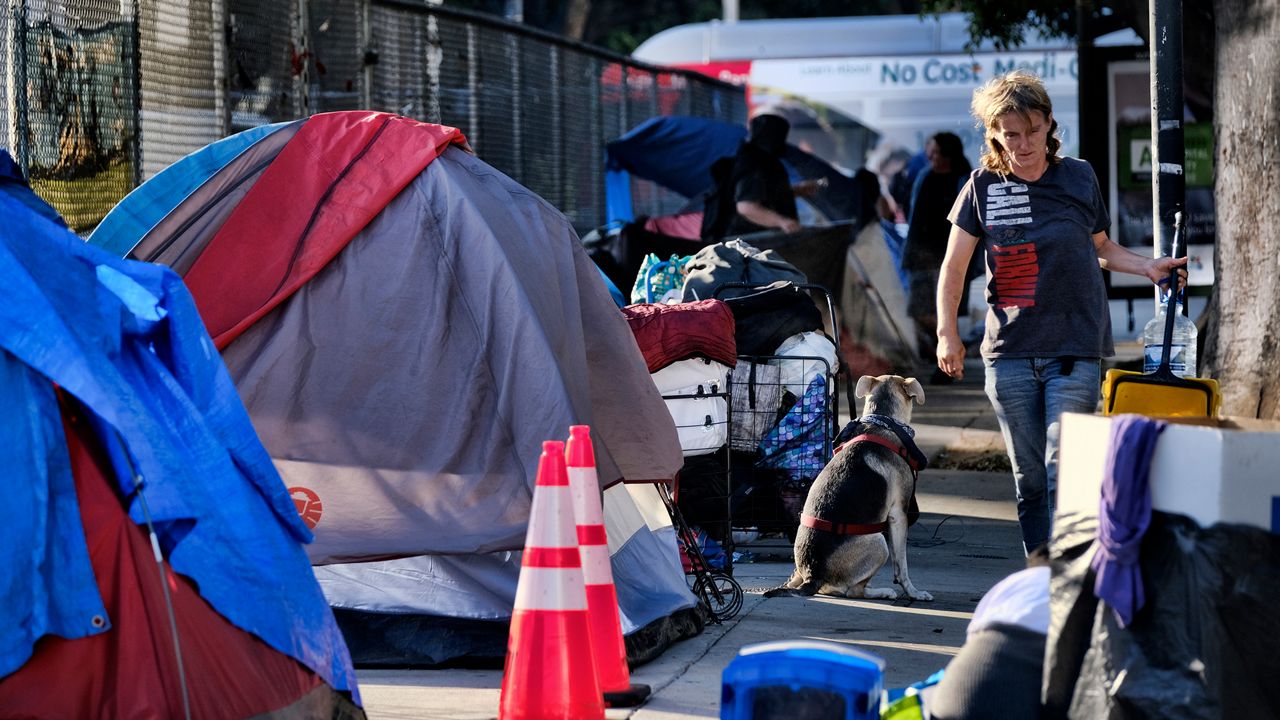 Homeless people move belongings from a street near Los Angeles City Hall as crews prepared to clean the area Monday, July 1, 2019. (AP Photo/Richard Vogel)