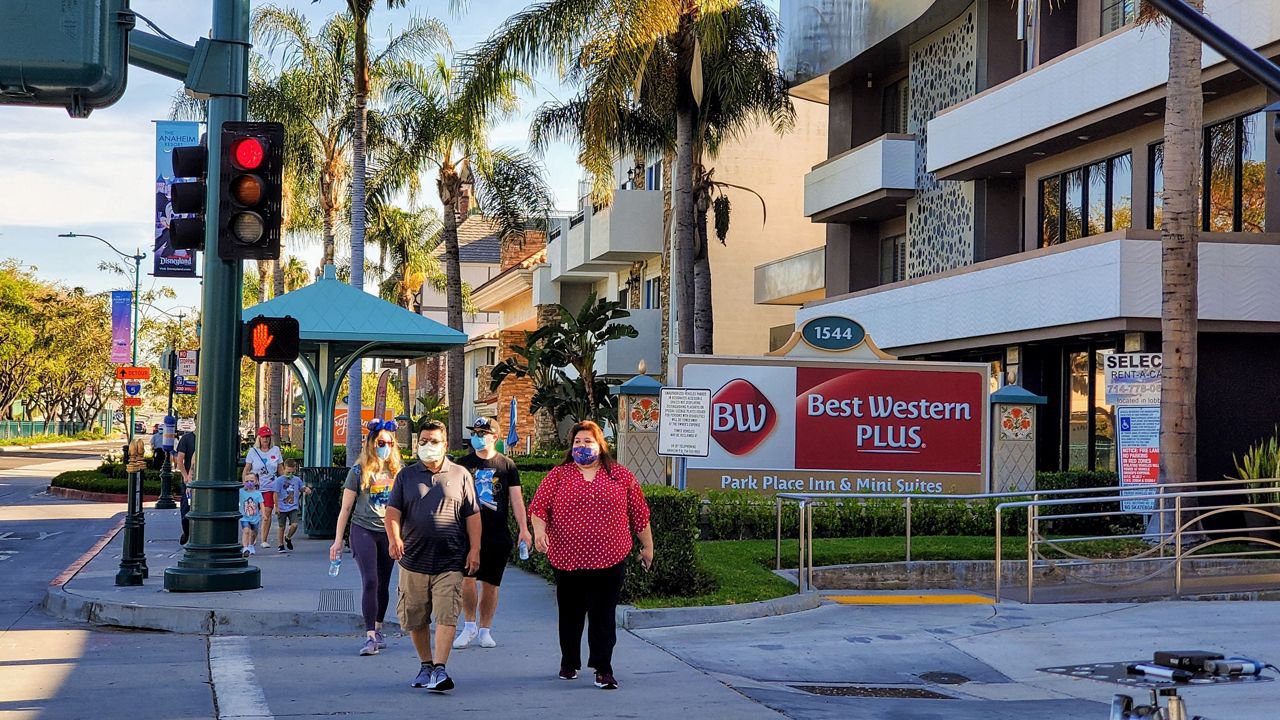 Visitors walk along the sidewalk of hotels across the street from Disneyland. (Spectrum News/Joseph Pimentel)