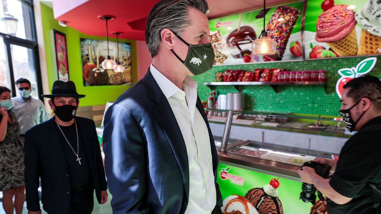 California Gov. Gavin Newsom and actor Danny Trejo visit Manzanitas Las Originales gourmet caramel apple shop downtown before signing legislation at a news conference in San Fernando, Calif. Thursday, April 29, 2021. (Robert Gauthier/Los Angeles Times via AP, Pool)
