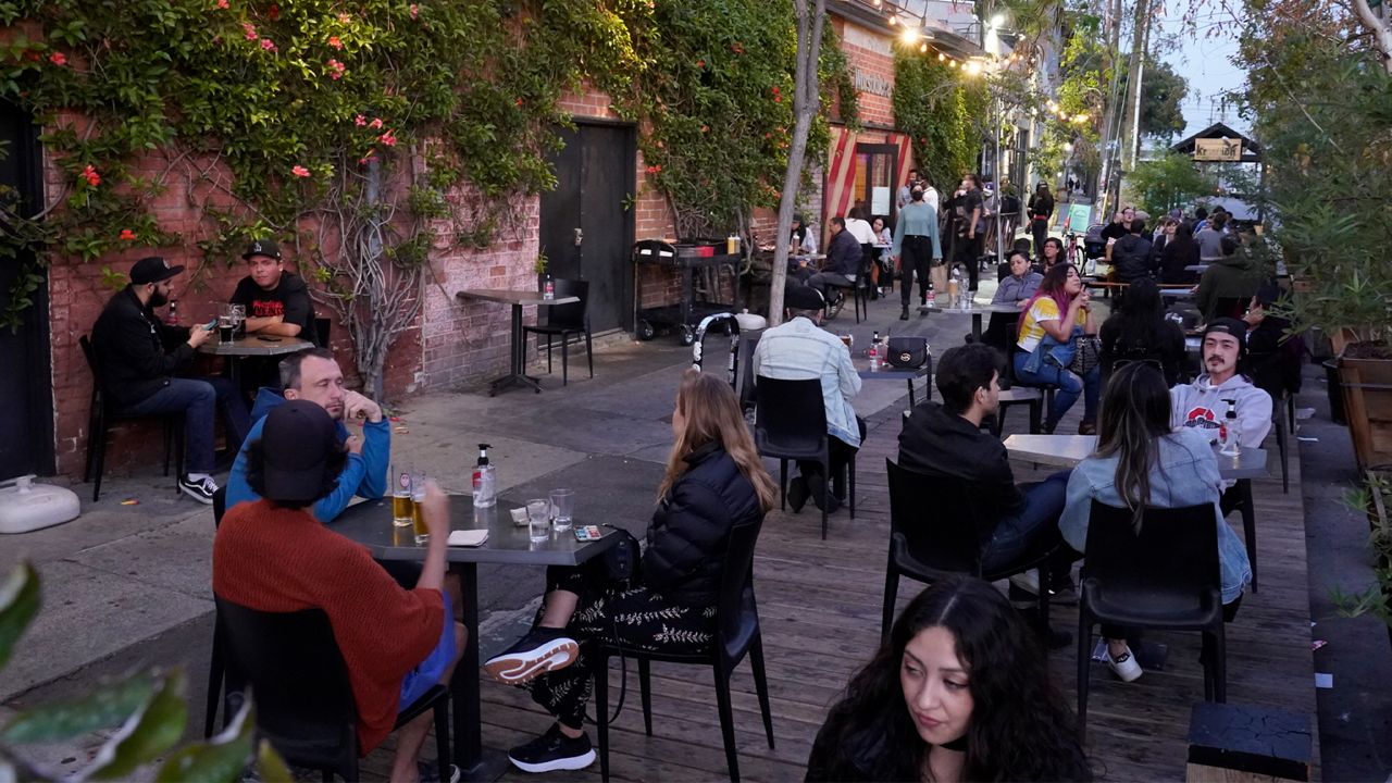 In this Sunday, May 2, 2021, photo, diners, some not wearing face masks, fill the sidewalk tables of Wurstküche, eating sausages and drinking Belgian and German beer in downtown Los Angeles. (AP Photo/Damian Dovarganes)
