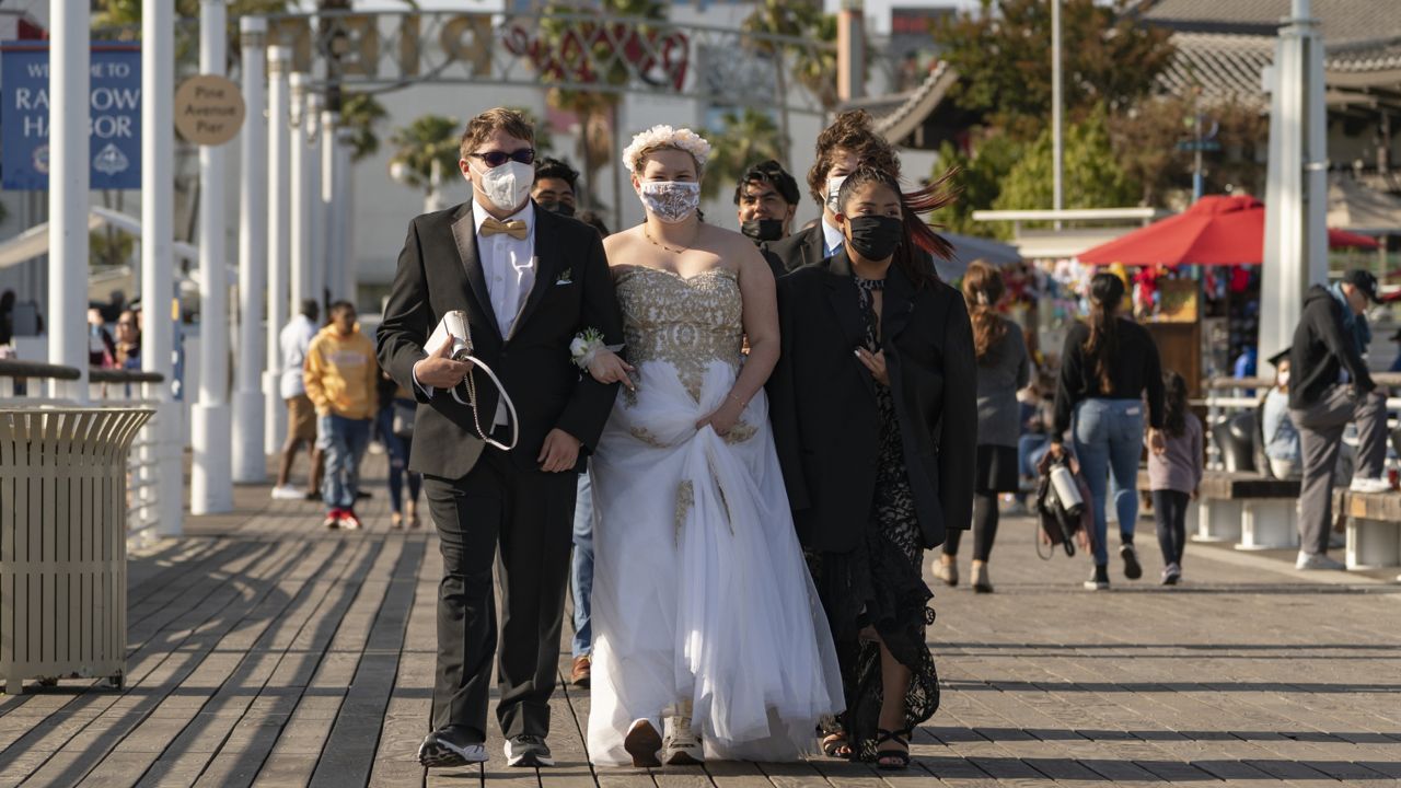 Wish Academy High School seniors wear facemasks as they walk on the pier to take pictures in Long Beach, Calif., Saturday, May 22, 2021. (AP Photo/Damian Dovarganes)