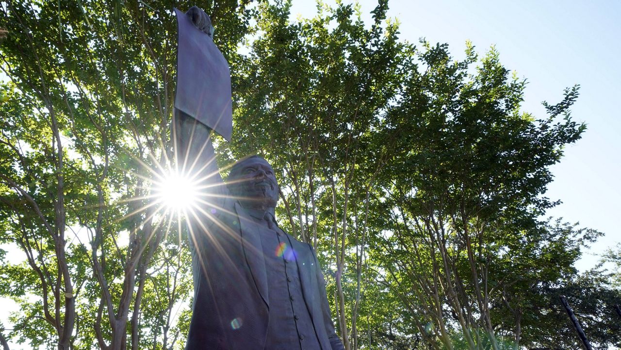 This June 17, 2020, photo, shows a statue depicting a man holding the state law that made Juneteenth a state holiday in Galveston, Texas. The inscription on the statue reads "On June 19, 1865, at the close of the Civil War, U.S. Army General Gordon Granger issued an order in Galveston stating that the 1863 Emancipation Proclamation was in effect. (AP Photo/David J. Phillip)