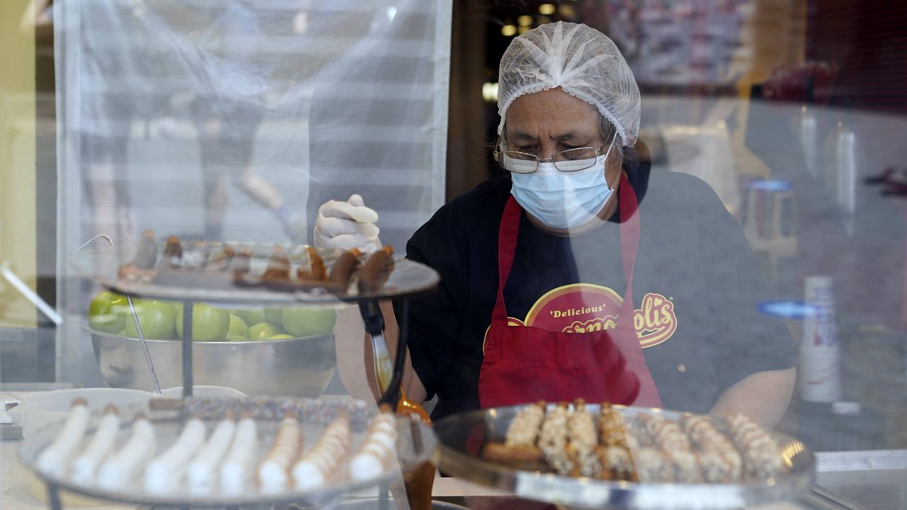 In this May 14, 2021 file photo a worker wears a mask while prepares desserts at the Universal City Walk, in Universal City, Calif. 